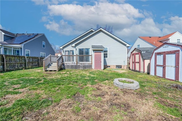 back of house with a lawn, a storage unit, a deck, and fence