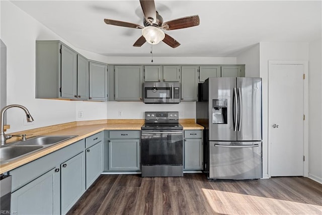 kitchen featuring dark wood-type flooring, ceiling fan, light countertops, appliances with stainless steel finishes, and a sink