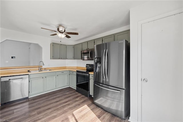 kitchen featuring dark wood finished floors, light countertops, stainless steel appliances, a ceiling fan, and a sink