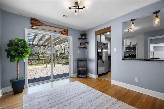 unfurnished dining area with light wood-style floors, visible vents, and baseboards