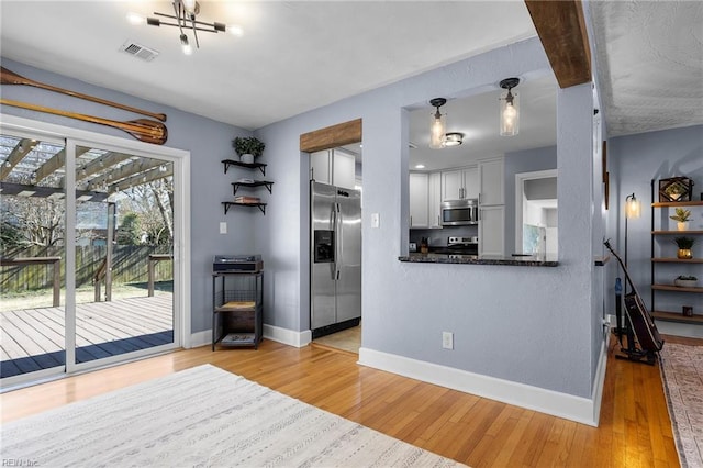 kitchen with stainless steel appliances, baseboards, visible vents, and light wood-style flooring