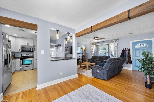 living room featuring beamed ceiling, baseboards, visible vents, and light wood finished floors