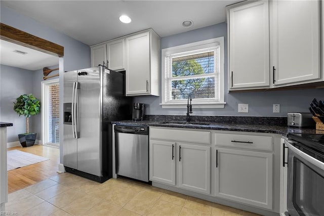 kitchen with visible vents, a sink, dark stone countertops, white cabinetry, and stainless steel appliances