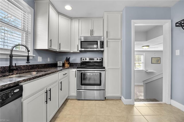 kitchen featuring a sink, light tile patterned floors, white cabinetry, and stainless steel appliances