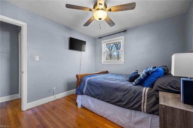 bedroom with baseboards, wood-type flooring, and a ceiling fan