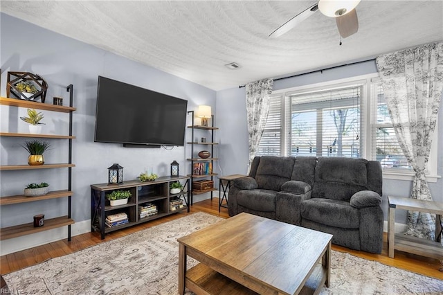 living room with a wealth of natural light, a textured ceiling, wood finished floors, and a ceiling fan