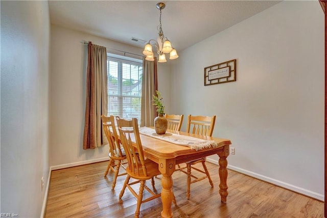 dining room with a notable chandelier, baseboards, and light wood-style floors