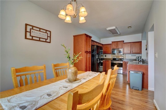 dining room with a notable chandelier, light wood-style flooring, visible vents, and baseboards