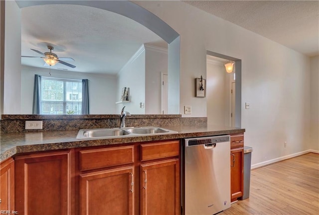 kitchen with brown cabinetry, arched walkways, a sink, a textured ceiling, and dishwasher