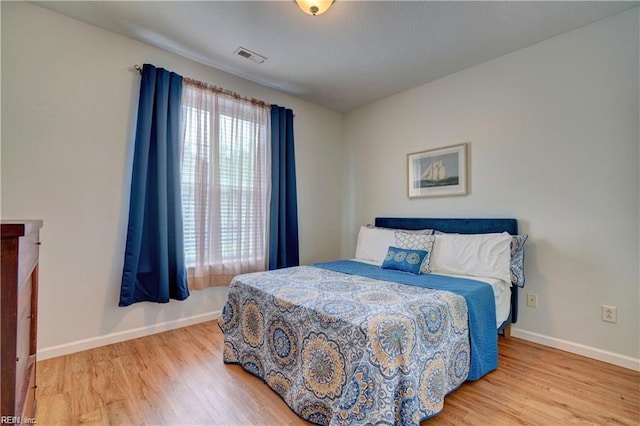 bedroom with visible vents, baseboards, and wood finished floors