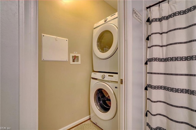 laundry area with stacked washer / drying machine, baseboards, and laundry area