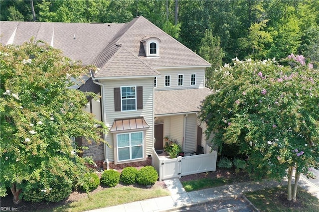 view of front of property featuring a fenced front yard, brick siding, roof with shingles, and a gate