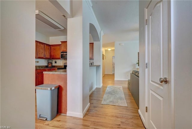 kitchen with crown molding, light wood-style flooring, baseboards, and appliances with stainless steel finishes