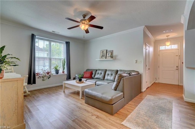 living room featuring light wood-type flooring, visible vents, ornamental molding, a textured ceiling, and baseboards