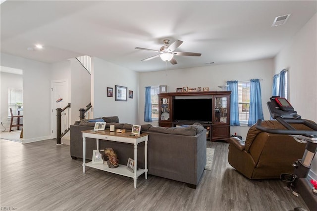 living room featuring visible vents, baseboards, stairway, wood finished floors, and a ceiling fan