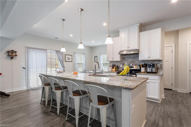 kitchen with a center island with sink, under cabinet range hood, a sink, stainless steel electric stove, and decorative backsplash