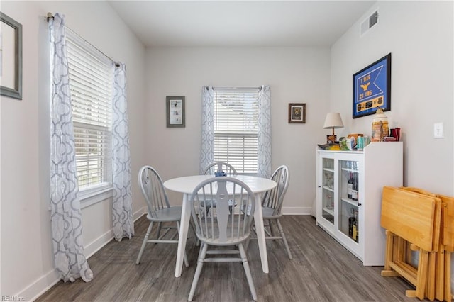 dining space featuring wood finished floors, visible vents, and baseboards