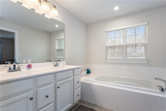 bathroom featuring double vanity, a garden tub, recessed lighting, and a sink