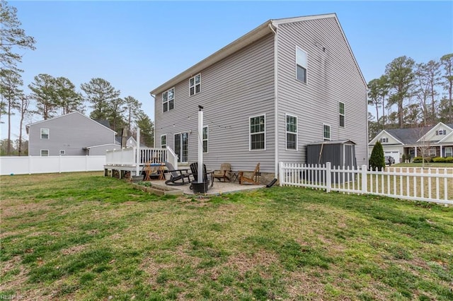 back of house with fence, an outdoor fire pit, a wooden deck, a yard, and a patio area