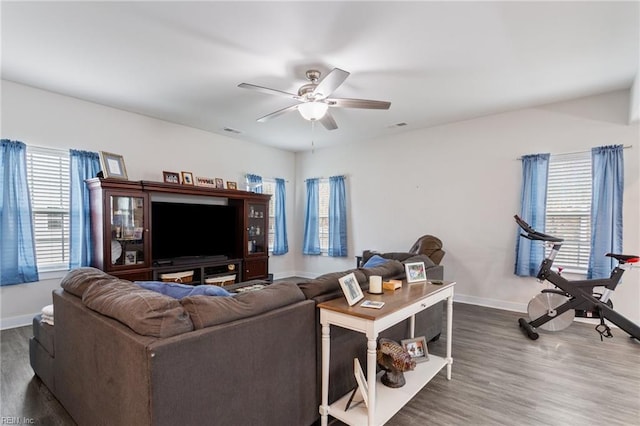 living area featuring visible vents, ceiling fan, baseboards, and wood finished floors