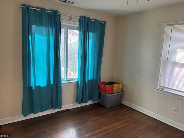 empty room with visible vents, baseboards, and wood finished floors