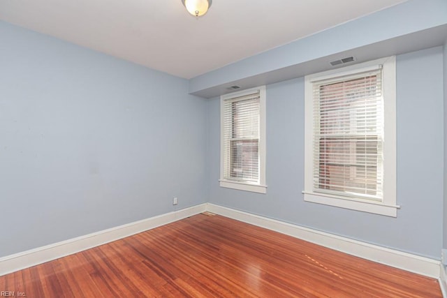 spare room featuring visible vents, wood finished floors, and baseboards