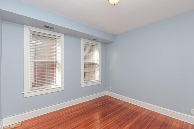 empty room with visible vents, baseboards, and wood finished floors