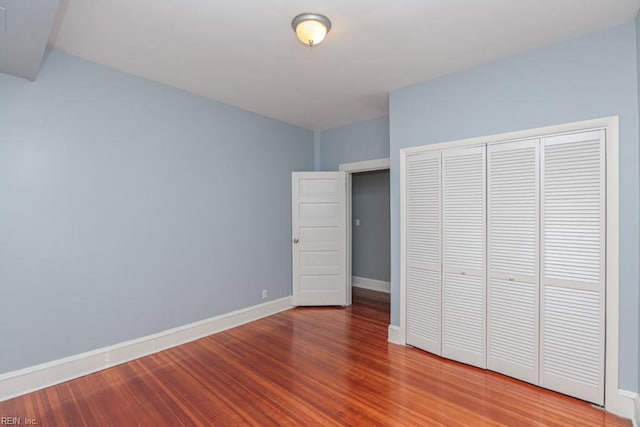 unfurnished bedroom featuring a closet, baseboards, and wood finished floors