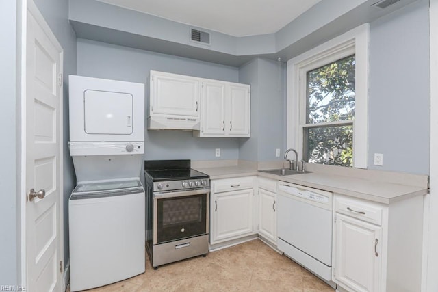 kitchen with visible vents, dishwasher, stacked washer and dryer, stainless steel range with electric cooktop, and a sink