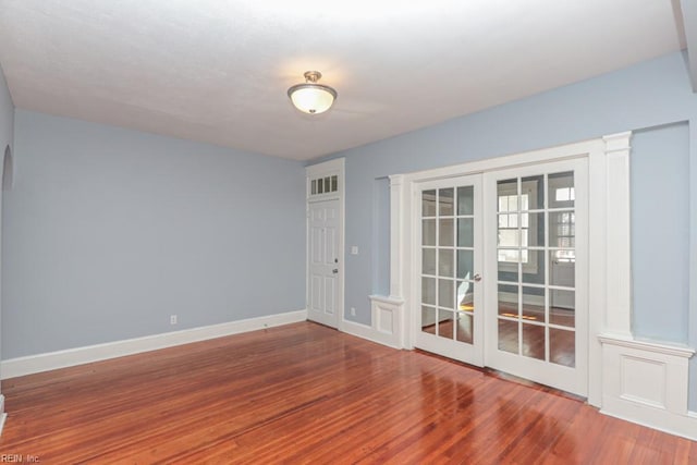 empty room featuring french doors, baseboards, and wood finished floors