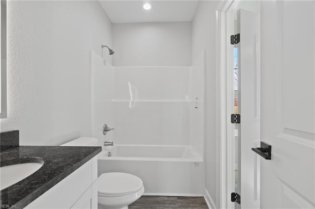 full bathroom with washtub / shower combination, toilet, wood finished floors, and vanity