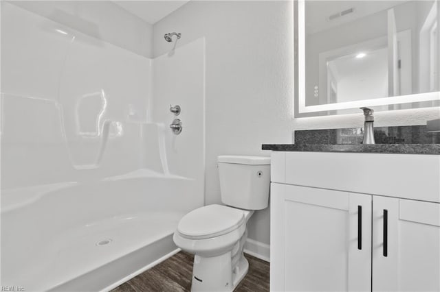 bathroom featuring vanity, toilet, a shower, and wood finished floors