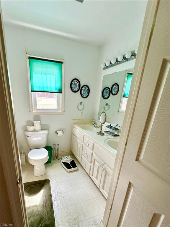 bathroom featuring tile patterned flooring, a sink, toilet, and double vanity