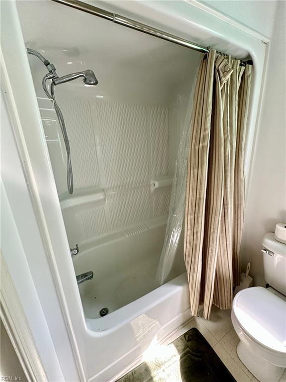 full bath with tile patterned flooring, toilet, and shower / bath combo