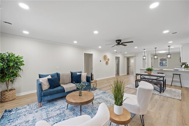 living area with recessed lighting, light wood-style floors, and ornamental molding