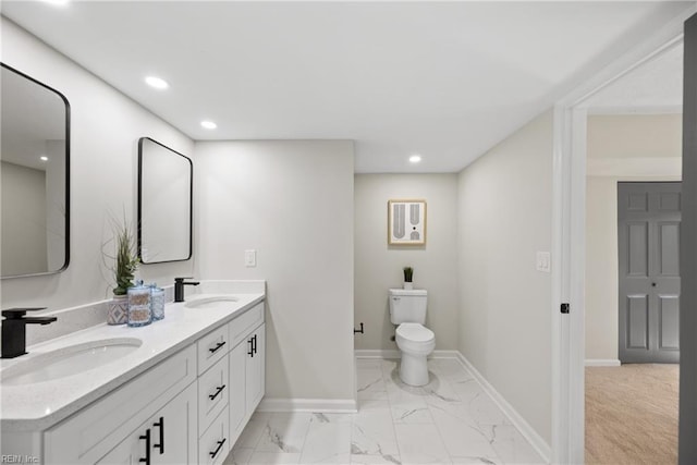 bathroom featuring double vanity, toilet, baseboards, and a sink