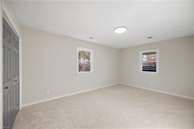 spare room with baseboards and light colored carpet