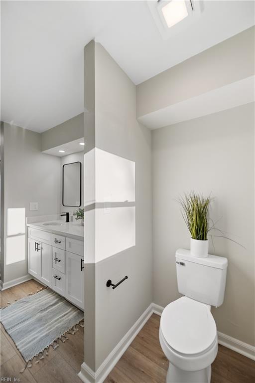 bathroom with toilet, baseboards, and wood finished floors