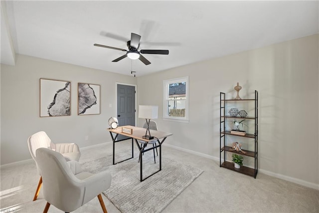 home office featuring light colored carpet, baseboards, and ceiling fan