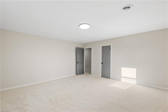 spare room with visible vents, light carpet, and baseboards