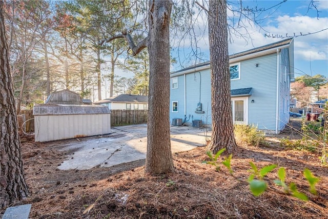 rear view of house featuring a storage unit, central air condition unit, fence, an outdoor structure, and a patio area