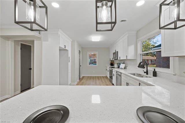 kitchen featuring a wealth of natural light, visible vents, a sink, appliances with stainless steel finishes, and light stone countertops