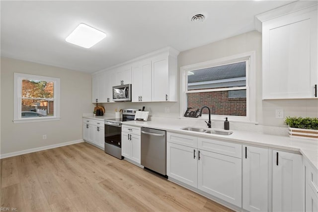 kitchen with light wood-type flooring, visible vents, a sink, white cabinetry, and stainless steel appliances