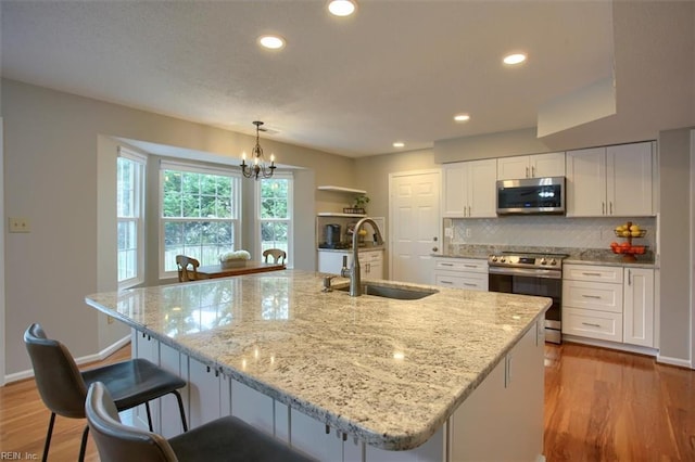 kitchen with a notable chandelier, white cabinets, stainless steel appliances, and a sink