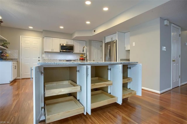 kitchen featuring appliances with stainless steel finishes, wood finished floors, and white cabinetry