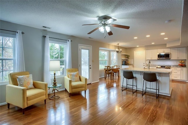 kitchen with dark wood finished floors, stainless steel microwave, visible vents, and a sink