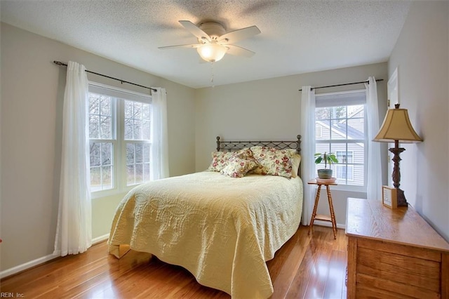 bedroom with a textured ceiling, baseboards, and wood finished floors