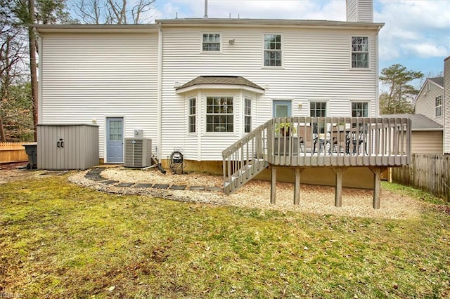 rear view of property with fence, a yard, central AC, a chimney, and a deck