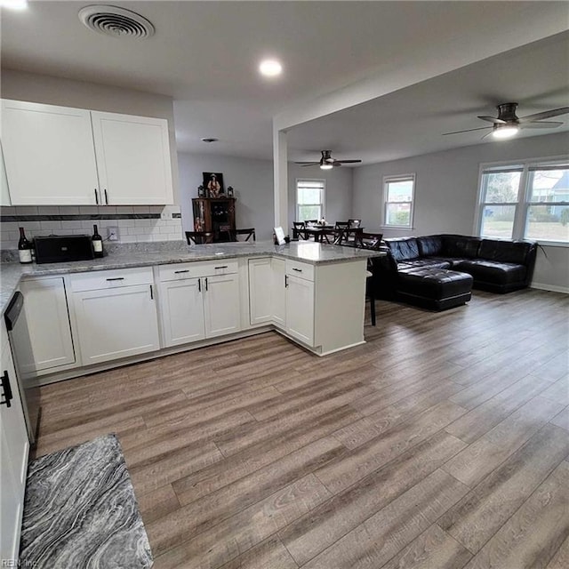 kitchen with visible vents, white cabinetry, light wood-type flooring, and open floor plan