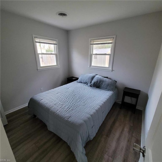 bedroom with baseboards, visible vents, and dark wood-style flooring